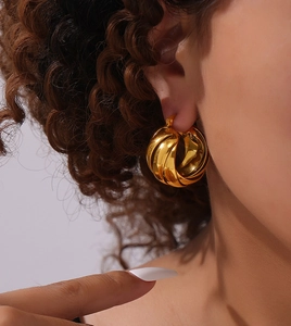 Detail of gold-plated chunky twist earrings with vintage textured pattern worn by a model