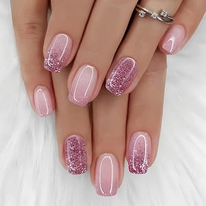 Close-up of pink glitter gradient press on nails on soft white plush background