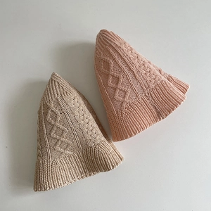 Close-up of knit fisherman hat with cable pattern and cute cat ear design in beige and pink