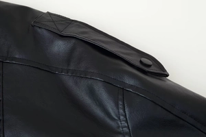 Detailed macro view of black faux leather texture with shoulder epaulet and metallic button