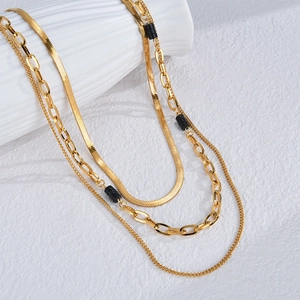 Collana bohémien a strati dorata con perline nere su un supporto in ceramica bianca