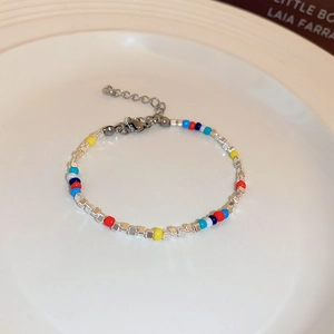 Macro detail of colorful beaded necklace with silver accents on a minimalist white plate