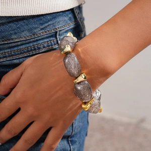 Close-up of gray glitter acrylic oval beads and golden triangular spacers on the bracelet