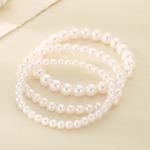 Drie elegante parelarmbanden met 5mm 6mm 8mm witte kralen op een crèmekleurige stof