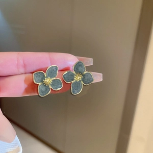 Macro view of blue enamel flower earrings with gold-toned metal petals and center