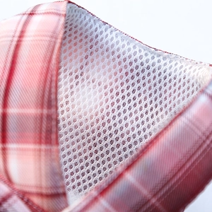 Detail of red and white plaid fabric with breathable white mesh lining on pet harness