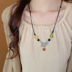 Detail of a vintage Chinese ceramic beaded necklace with Fu character charm on a woven cord