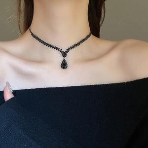 Macro detail of a black rhinestone choker necklace with a drop pendant on a model