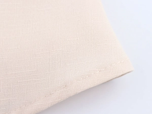 Macro della trama di lino beige con cuciture pulite sul bordo dell'orlo rifinito