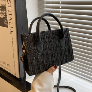 Classic black woven crossbody bag with leather handle and golden hardware in lifestyle setting