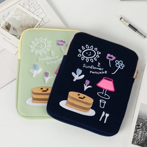 Close-up of embroidered sunflower and pancake patterns on protective laptop sleeves