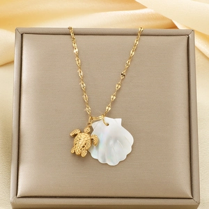 Detail of 18K gold tortoise and natural white shell pendants on a wavy gold chain
