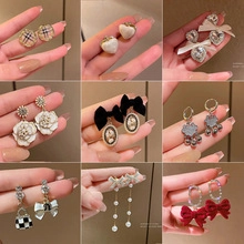 Detailed collection of paw-shaped earrings with zircons and various stylish charms