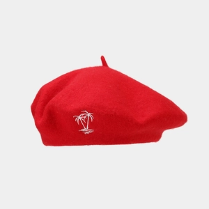 Detail of red wool beret showing premium fabric texture and white coconut tree embroidery