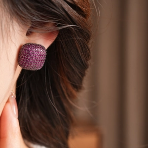 Vue macro de boucles d'oreilles carrées avec cristaux magenta sertis sur métal noir
