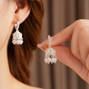 Detailed close-up of silver Jhumka earrings with zircon accents and pearl tassel dangles