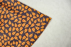 Macro shot of orange leaf print on purple fabric with double-needle stitching detail