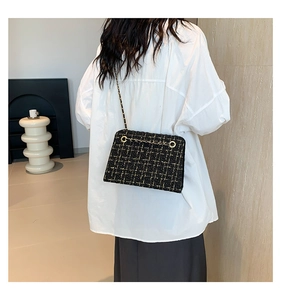 Detail of tweed shoulder bag with golden chain strap on a model for a stylish look