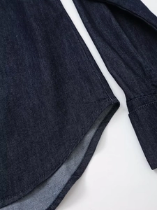 Vue détaillée d'une chemise en jean bleu foncé avec coutures denses et ourlet arrondi