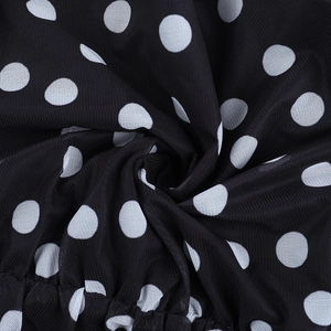 Detailaufnahme von schwarzem Netzstoff mit weißen Punkten und eleganten Faltenstrukturen