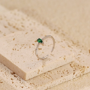 Close-up of s925 silver ring with green emerald zircon on natural stone base