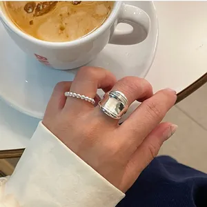 Polished 925 sterling silver geometric rings shown with beads and wide band in a lifestyle setting