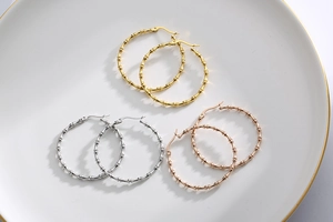 Detailed view of bamboo style hoop earrings in gold, silver, and rose gold finishes