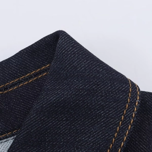 Gros plan détaillé du tissu denim bleu foncé avec double couture orange contrastée