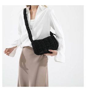 Detail view of black pleated cloud bag texture and thick ruffled shoulder strap on model