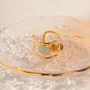 Detailed close-up of three colorful natural stones set on a triple-layer gold ring