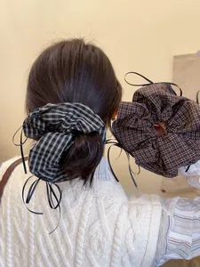 Close-up of plaid fabric scrunchie with long black ribbon detail for low ponytail styles
