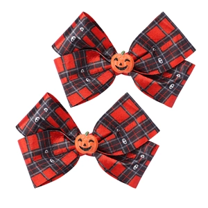 Close-up of Halloween red and black plaid bow hair clips with orange pumpkin smile centers
