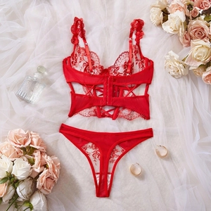 Flat lay of red floral lace lingerie set with perfume and roses on white mesh background