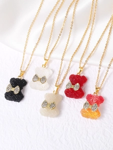 Dettaglio di ciondoli a forma di orsetto in resina con fiocchi di strass e catene oro