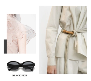 Close-up of black oval sunglasses paired with a beige shirt and pink ruffled top