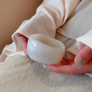 Close-up of a minimalist creamy white thick bangle with a smooth polished finish