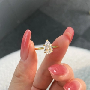 Macro shot of gold teardrop zircon ring held by hand showing sparkling details