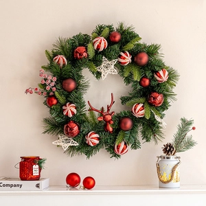 Christmas wreath with red baubles, stars, and reindeer head hanging on a beige wall