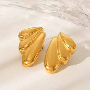 Detailed macro shot of golden wing earrings with polished finish on a glass base