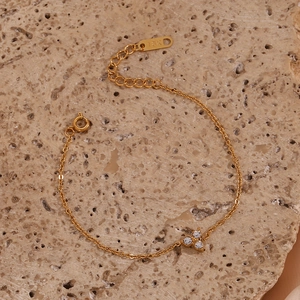 Detail of 18K gold-plated stainless steel bracelet with zircon lotus pendant on stone