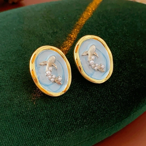 Detailed shot of vintage gold koi fish earrings with blue enamel and faux pearls