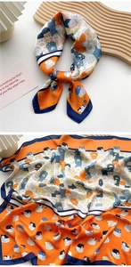 Detail of silk scarf with cat print and paw patterns in orange and navy blue