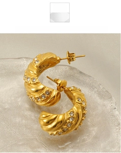 Détail de boucles d'oreilles créoles dorées 18 carats avec texture spirale et zircons