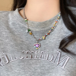 Detail view of a heart pendant necklace with colorful rhinestones on a layered beaded chain