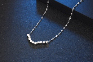 Detailed view of silver titanium steel necklace featuring small square charms on a chain
