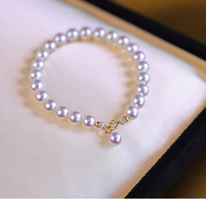 Close-up of pearl bracelet with golden spring clasp and round white pearls on silk padding