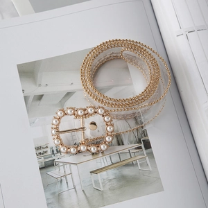 Detail of transparent PVC belt with gold chain trim and pearl-encrusted oval buckle