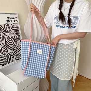 Nahaufnahme der blauen Karo-Stofftasche mit rosa Trägern und Markenlogo-Aufnäher