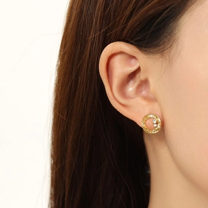 Close-up of gold hollow hoop earrings with zircon inlay worn by a model
