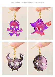 Macro detail of gothic skull earrings with gold foil and purple resin gradient